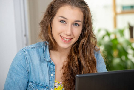 一位留着长发微笑的年轻女子正在使用笔记本电脑