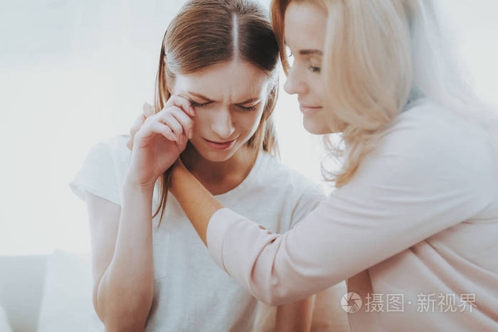 女人在家安慰不幸的十几岁的女儿. 坐在家里的沙发上.