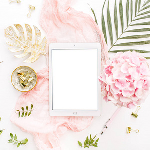 空白屏幕平板，粉红色绣球花束，热带棕榈叶糊状毛毯，叶子板和配件在白色背景。 平躺顶部视图玫瑰金家庭办公桌工作区模型。