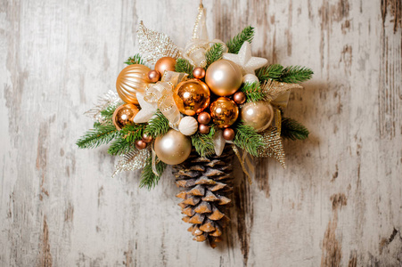 圣诞墙装饰由冷杉锥制成，有金色的球和新鲜的绿色树枝