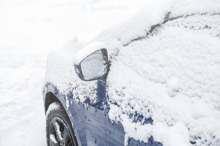 汽车翼镜上的雪。冰冻的汽车，蓝色的汽车在冬天覆盖着雪。冬季城市生活的城市场景。