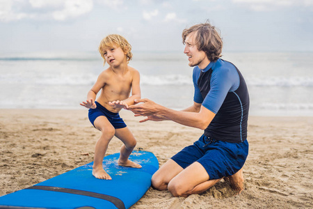 父亲教小儿子在海边沙滩冲浪图片