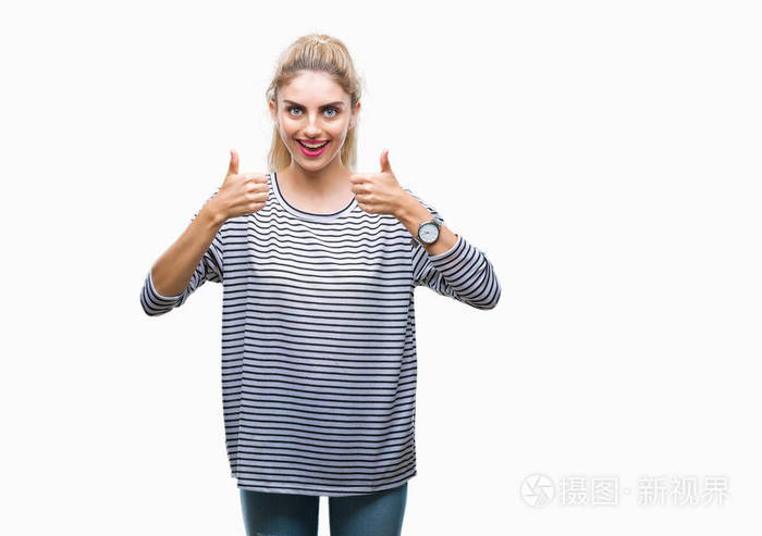 年轻漂亮的金发女人穿着条纹毛衣在孤立的背景上做积极的手势用手竖起