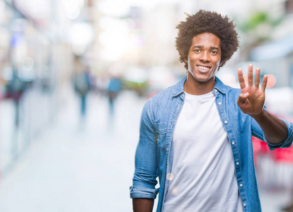 美国黑人男子在孤立的背景显示和指着第四个手指，同时微笑自信和快乐。