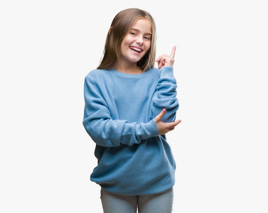 年轻漂亮的女孩穿着冬天的毛衣，在孤立的背景上，脸上挂着一个大大的微笑，用手和手指指向一边，看着相机。