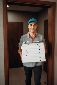 送货员带新鲜披萨在纸箱里送服务。 Pizzeria的快递员在室内存放纸板包裹