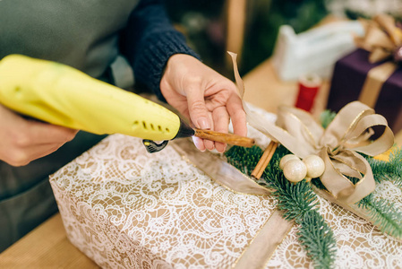 圣诞礼品盒包装和装饰杉木分公司。 女人包在桌子上，装饰程序，节日包装