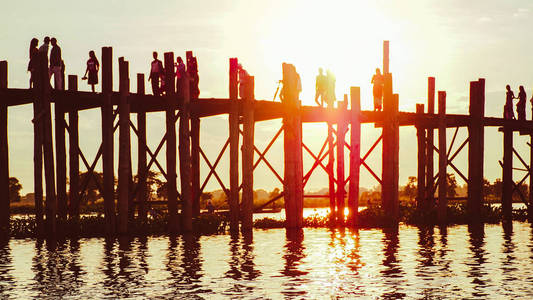 夕阳西下，人们在桥上行走，傍晚时分，缅甸的马拉普拉曼德勒
