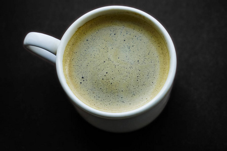 黑色咖啡在咖啡白色杯子顶部视图隔离在棕色背景。