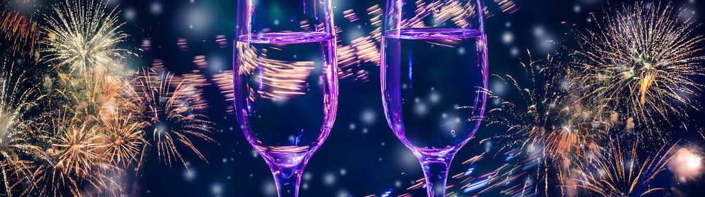 五颜六色的烟花和两杯葡萄酒，香槟与气泡特写在飘落的雪背景。