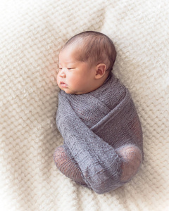 出生的亚洲小男孩包着紫色针织马海毛。可爱的肖像6天大婴儿躺在床上舒适的毯子背景