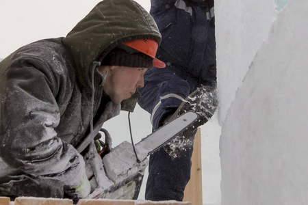工作安装人员在一个保护头盔与电锯在他们的手中从事安装冰结构与一个助手