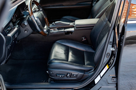 舒适的前排座位在车内司机和乘客系着真正的黑色皮革现代室内设计，方向盘覆盖棕色木材和豪华的中控台。