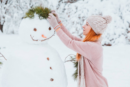 在公园堆雪人的年轻女子