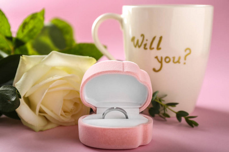 盒子上有漂亮的订婚戒指和玫瑰色背景