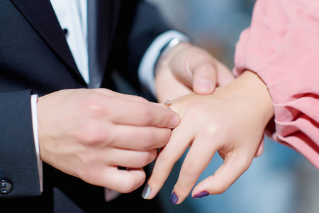 新郎把戒指戴在手指上。 快乐的一对。 带戒指的盒子。 女性和男性的手。 婚礼和订婚戒指。 一个年轻人向他女朋友求婚。