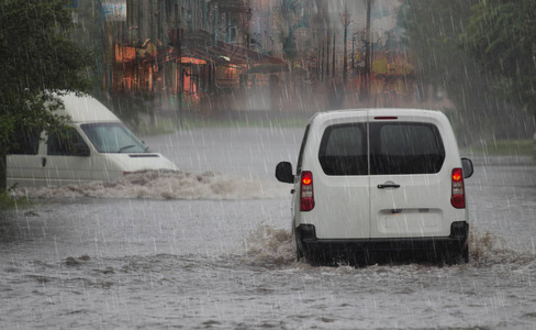 下雨天，一条被洪水淹没的城市道路上的汽车。