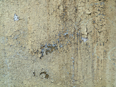旧墙上的灰色裂缝油漆。 被时间和天气破坏的背景表面