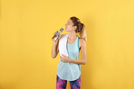 穿着运动服的漂亮年轻女子，带毛巾和一瓶水在彩色背景上