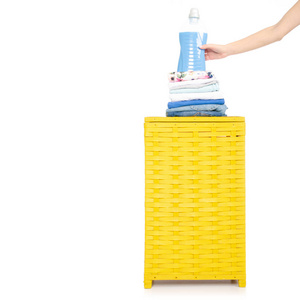 黄色洗衣篮，配有柔软剂干燥器，手拿白色背景隔离