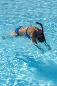 女人在游泳池里潜水。 年轻漂亮的女孩在游泳池里游泳。 在阳光明媚的日子里，黑发女人在清澈的温水中放松。 顶部视图关闭慢速运动。 