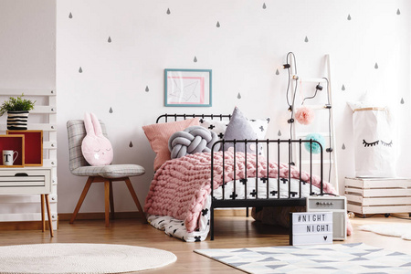 斯堪的纳维亚卧室内部的单人工业床上舒适的粉彩粉色毛毯，供青少年使用