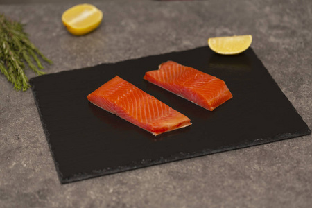 生的新鲜美味的鲑鱼牛排放在黑色石板上。 野生大西洋鱼