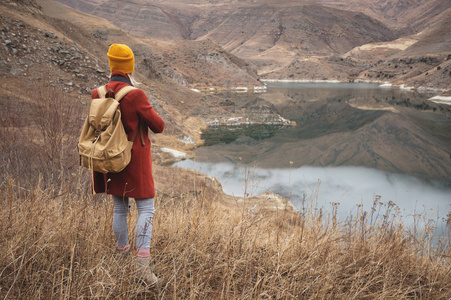 秋天或初春, 一位女旅行者在山上的一个湖的背景上的画像。旅游理念