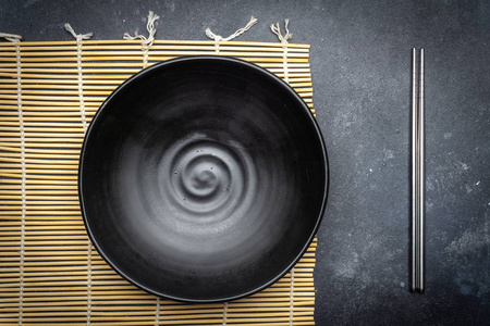空盘子暗色和中国筷子在黑暗的背景上。 亚洲风格的亚洲美食。 复制空间。