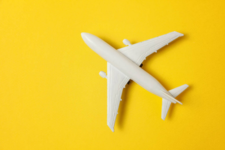 简单的平躺设计微型玩具模型平面上的黄色彩色纸潮流背景。 乘飞机旅行，暑假，周末，海上冒险旅行，旅程，机票，旅游概念