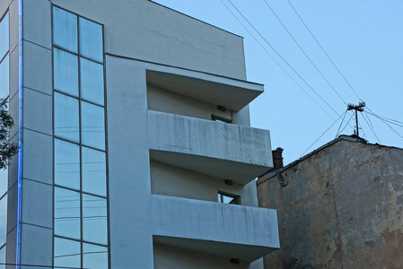 一座混凝土建筑上的灰色阳台和窗户靠在旧墙上