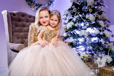 幸福的家庭母女和女儿在圣诞树附近豪华礼服。家庭外观。新年快乐和圣诞节主题。节日心情