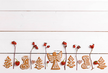 圣诞自制姜饼饼干和红玫瑰浆果, 放在白色木桌上。圣诞横幅。t