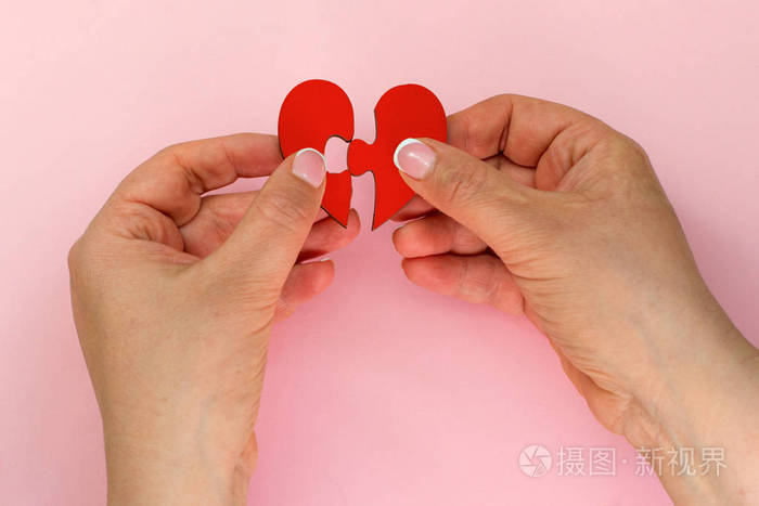 两只手拿着连接两块拼图,爱心拼图,爱的概念.