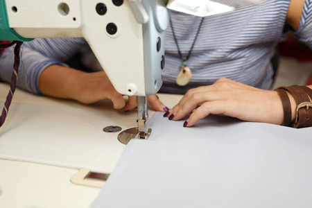 从上面看，女裁缝在缝纫机上工作。 服装制造业。