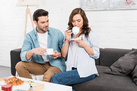 一对夫妇在家吃早餐时坐在沙发上喝咖啡