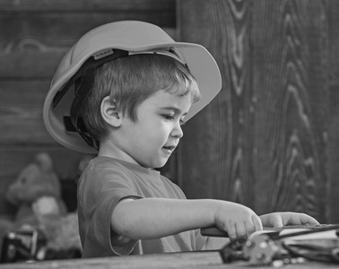 孩子在桌子上玩工具。就要手工制作概念。儿童在头盔可爱的发挥建设者或维修, 修理或就要手工制作。幼儿在繁忙的面孔在家在车间演奏
