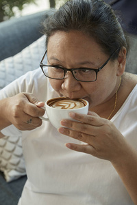 在咖啡店喝咖啡的漂亮女人的户外肖像。 焦点