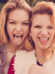 两个十几岁的疯狂时髦女人玩得很开心，笑得很开心，一个伸出舌头。