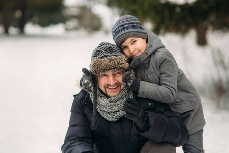 愉快的父亲与他的儿子穿过公园在下雪的冬天天气
