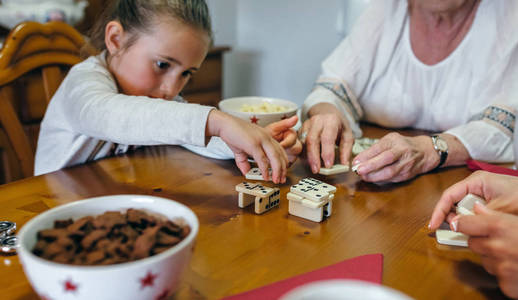小女孩玩多米诺骨牌与母亲和祖母