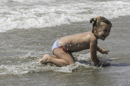 可爱的女婴在海边玩耍，在阳光明媚的沙滩上放松