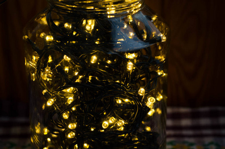 圣诞灯。装饰灯。温暖的白色LED灯。在黑暗中，一个格子桌布上的罐子里的圣诞灯装饰。