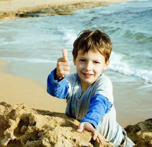 小可爱的真正的男孩在玩石头海海岸大拇指