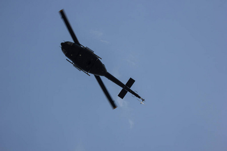 在蓝天上飞行的黑色直升机