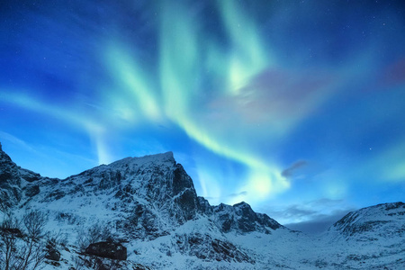 挪威洛夫顿群岛上的北极光。 群山之上的绿色北极光。 夜空中有极地的灯光。 夜间冬季景观与极光。 挪威的自然背景