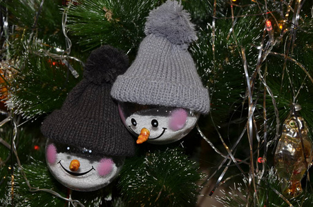 挂在树上的圣诞玩具。 两个穿针织帽子的雪人