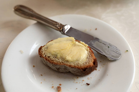 有黄油的面包在餐馆的白色盘子里
