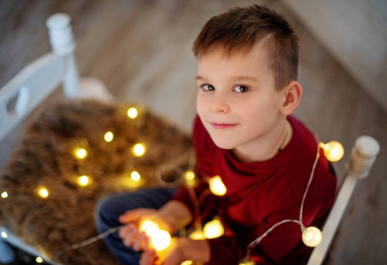 可爱的小男孩在地板上玩圣诞灯