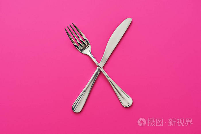 刀和叉子交叉 隔离在粉红色的背景